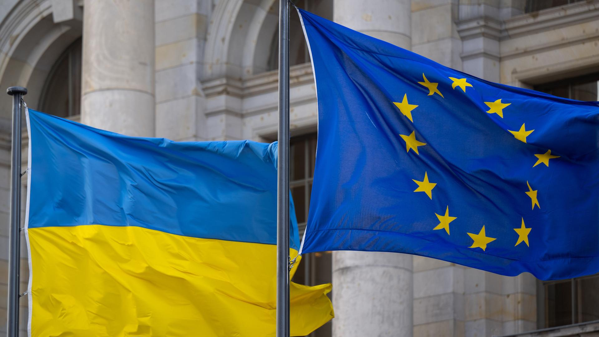 Die Nationalflagge der Ukraine und die Flagge der EU wehen im Wind.