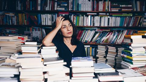 Die Autorin Asal Dardan posiert zwischen vielen Büchern
