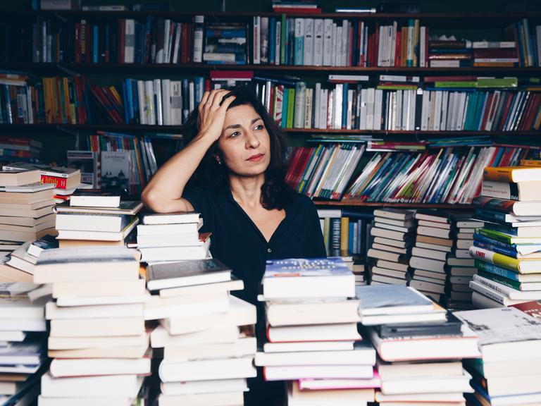 Die Autorin Asal Dardan posiert zwischen vielen Büchern