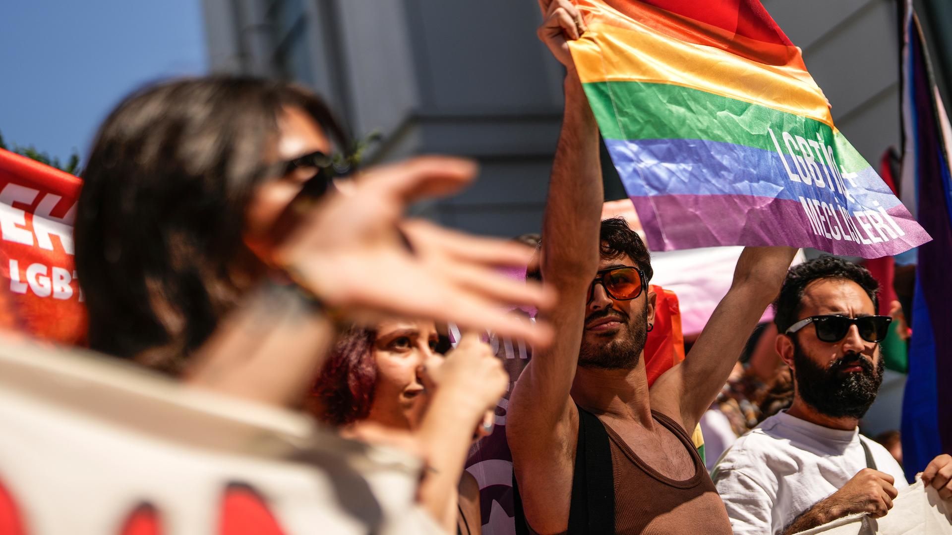 Mehrere Menschen tragen Regenbogenflaggen und Transparente vor sich her