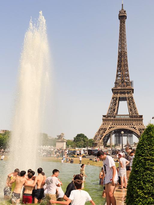Hitzewelle mit Temperaturen bis zu 42°C in Frankreich in Paris am 18. Juni 2022. Menschen baden im Springbrunnen vor dem Eiffelturm.