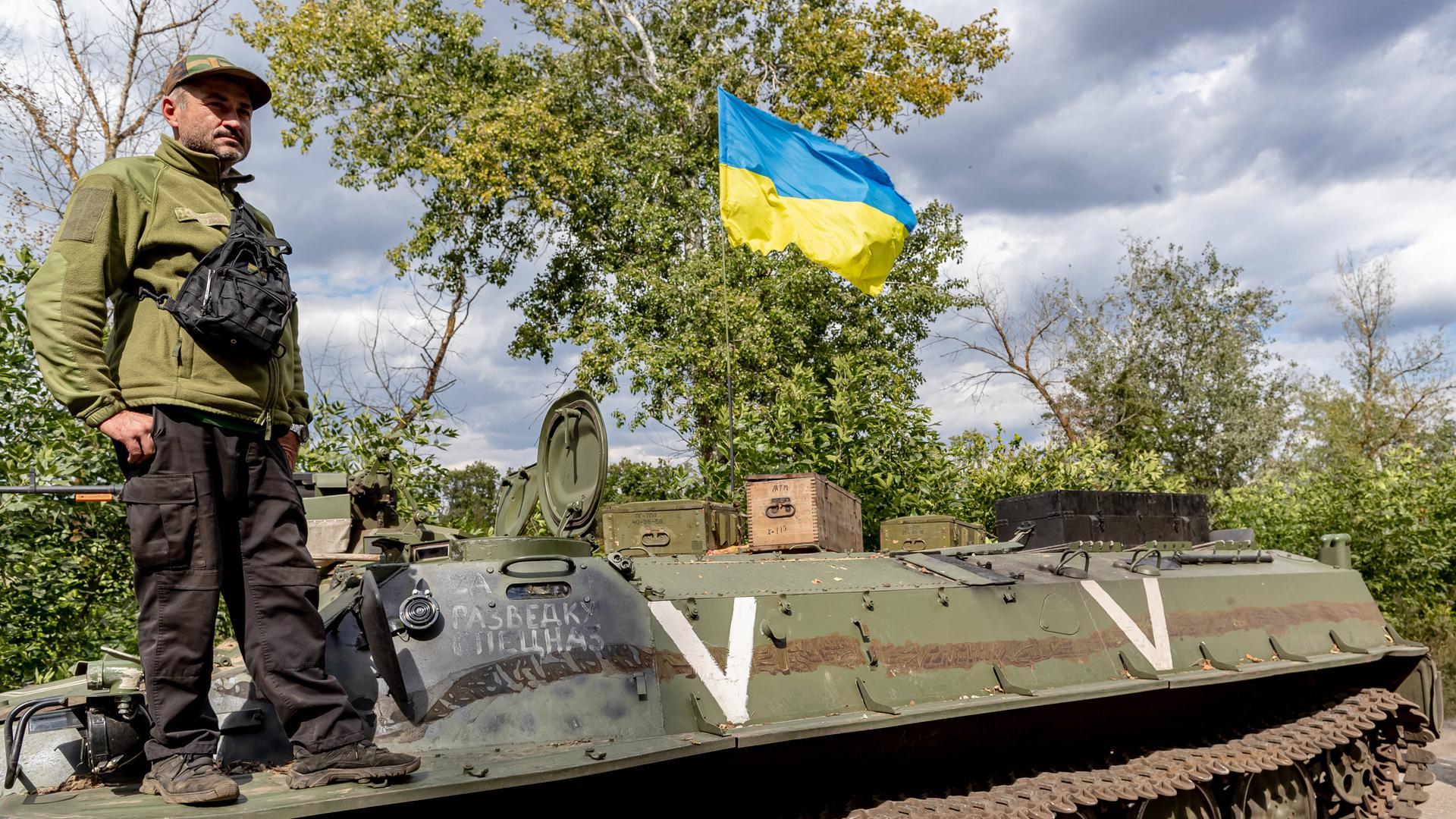 Ein ukrainischer Soldat und eine ukrainische Nationalflagge stehen auf einem verlassenen russischen Panzer, der von den ukrainischen Streitkräften in der Ostukraine am 8. September 2022 erbeutet wurde
