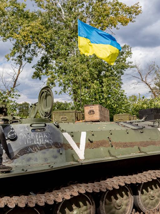 Ein ukrainischer Soldat und eine ukrainische Nationalflagge stehen auf einem verlassenen russischen Panzer, der von den ukrainischen Streitkräften in der Ostukraine am 8. September 2022 erbeutet wurde