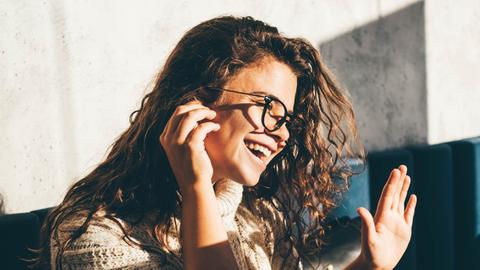 Treibt Mirjam Eichfeld den Anrufer vom Meinungsforschungsinstitut in den Wahnsinn oder in eine Romanze? Zu sehen: Eine junge Frau mit lockigem Haar, einer schwarzen Brille, lacht und hat ein  Smartphone am Ohr.