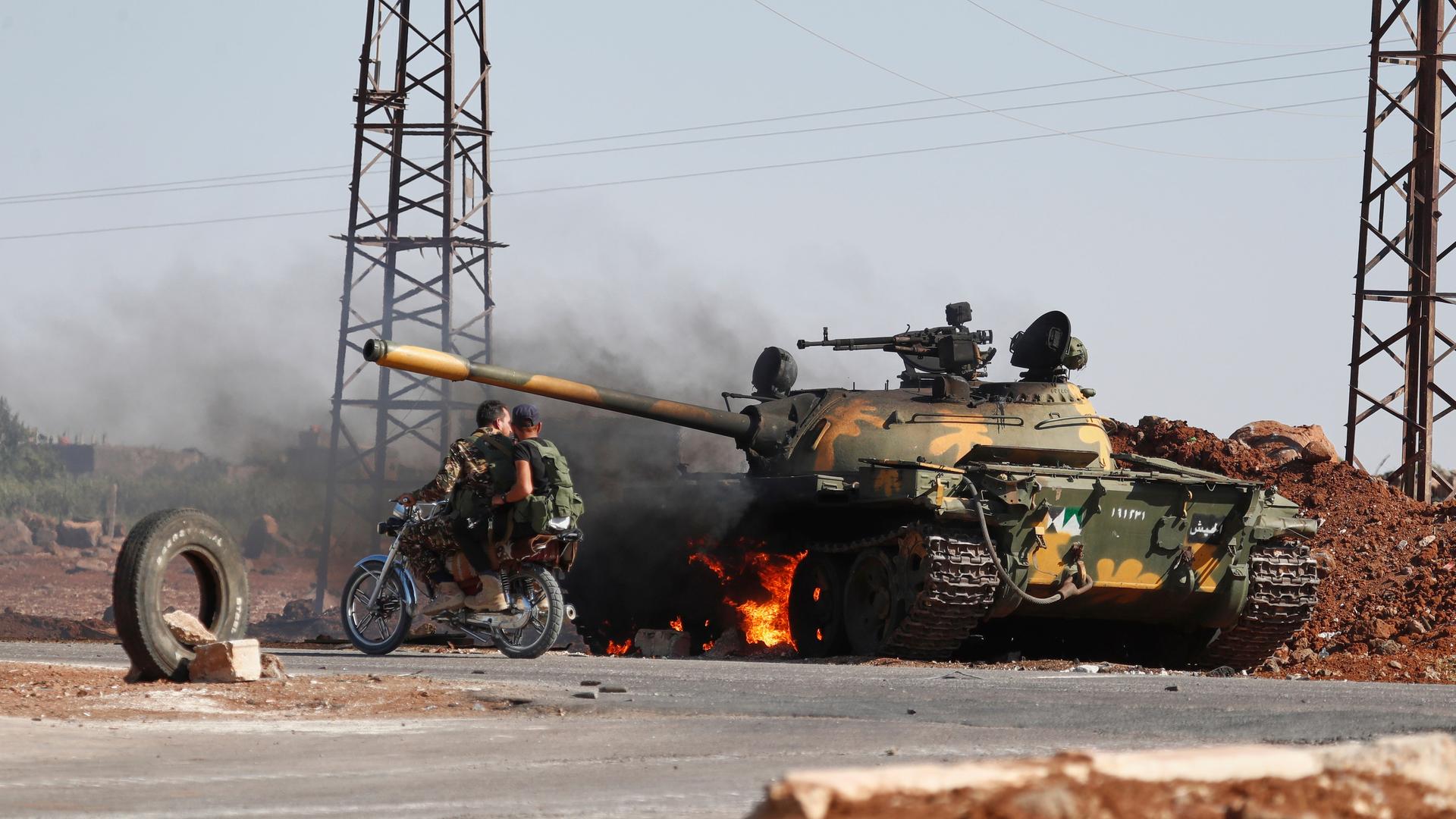 Syrische Regierungssoldaten fahren auf einem Motorrad an einem brennenden Panzer am Stadtrand von Sweida vorbei, wo es zu Zusammenstößen zwischen drusischen Milizen und sunnitischen Beduinenclans gekommen ist. Syrische Regierungssoldaten fahren auf einem Motorrad an einem brennenden Panzer am Stadtrand von Sweida vorbei, wo es zu Zusammenstößen zwischen drusischen Milizen und sunnitischen Beduinenclans gekommen ist.