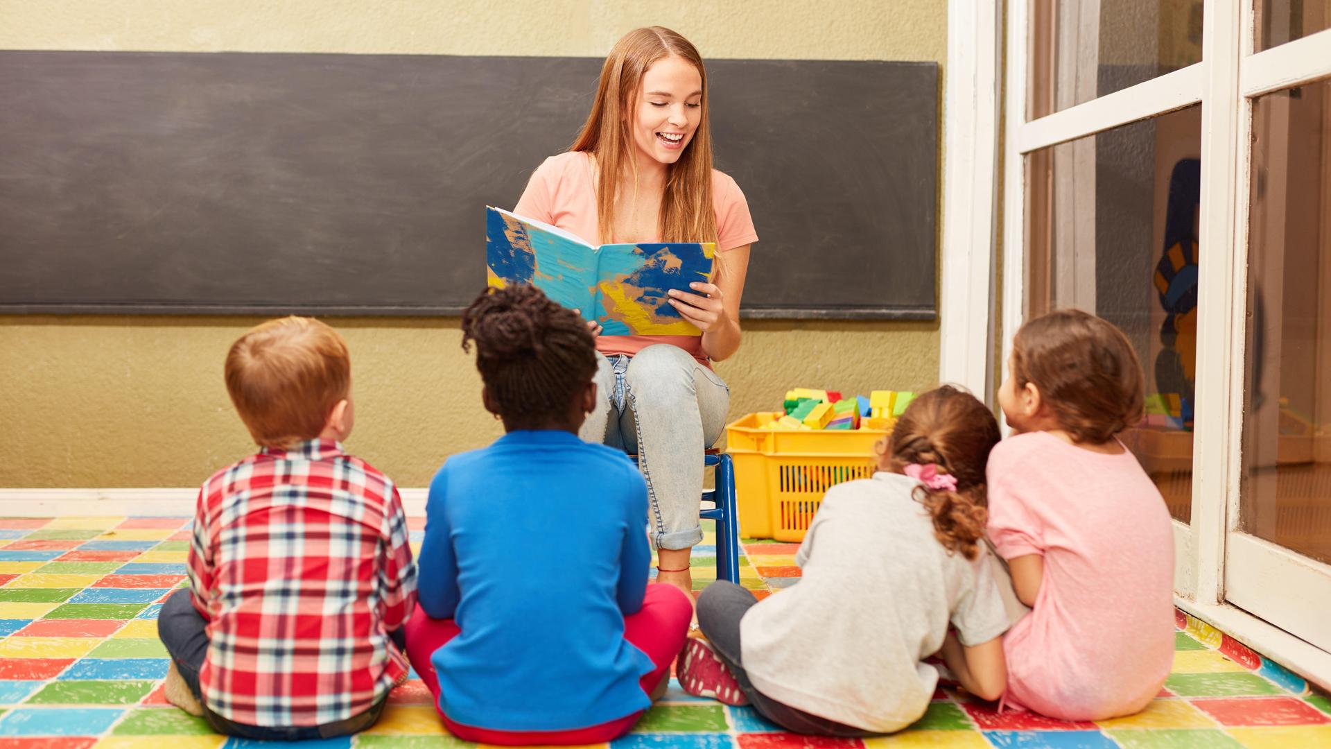 Eine Erzieherin liest Kindern aus einem Buch vor.