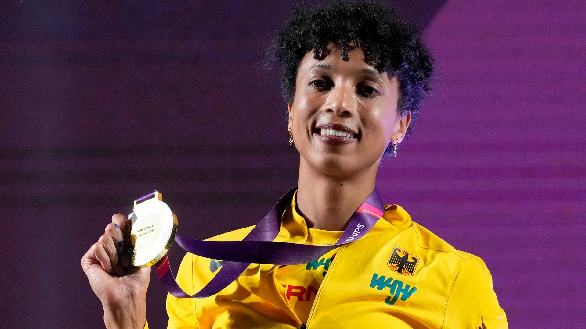 Malaika Mihambo jubelt bei der Siegerehrung und zeigt den Fotografen die Goldmedaille.