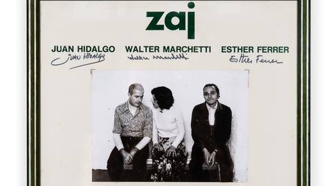 Eine gerahmte Einladungskarte zu einer Veranstaltung von "Zaj" mit einem schwarz/weiß-Foto von Juan Hidalgo, Walter Marchetti und Esther Ferrer
 
