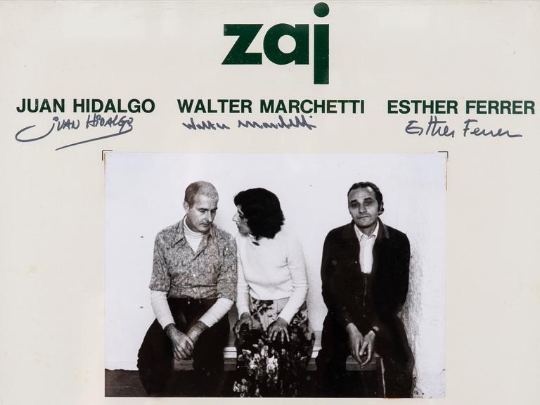 Eine gerahmte Einladungskarte zu einer Veranstaltung von "Zaj" mit einem schwarz/weiß-Foto von Juan Hidalgo, Walter Marchetti und Esther Ferrer
 
