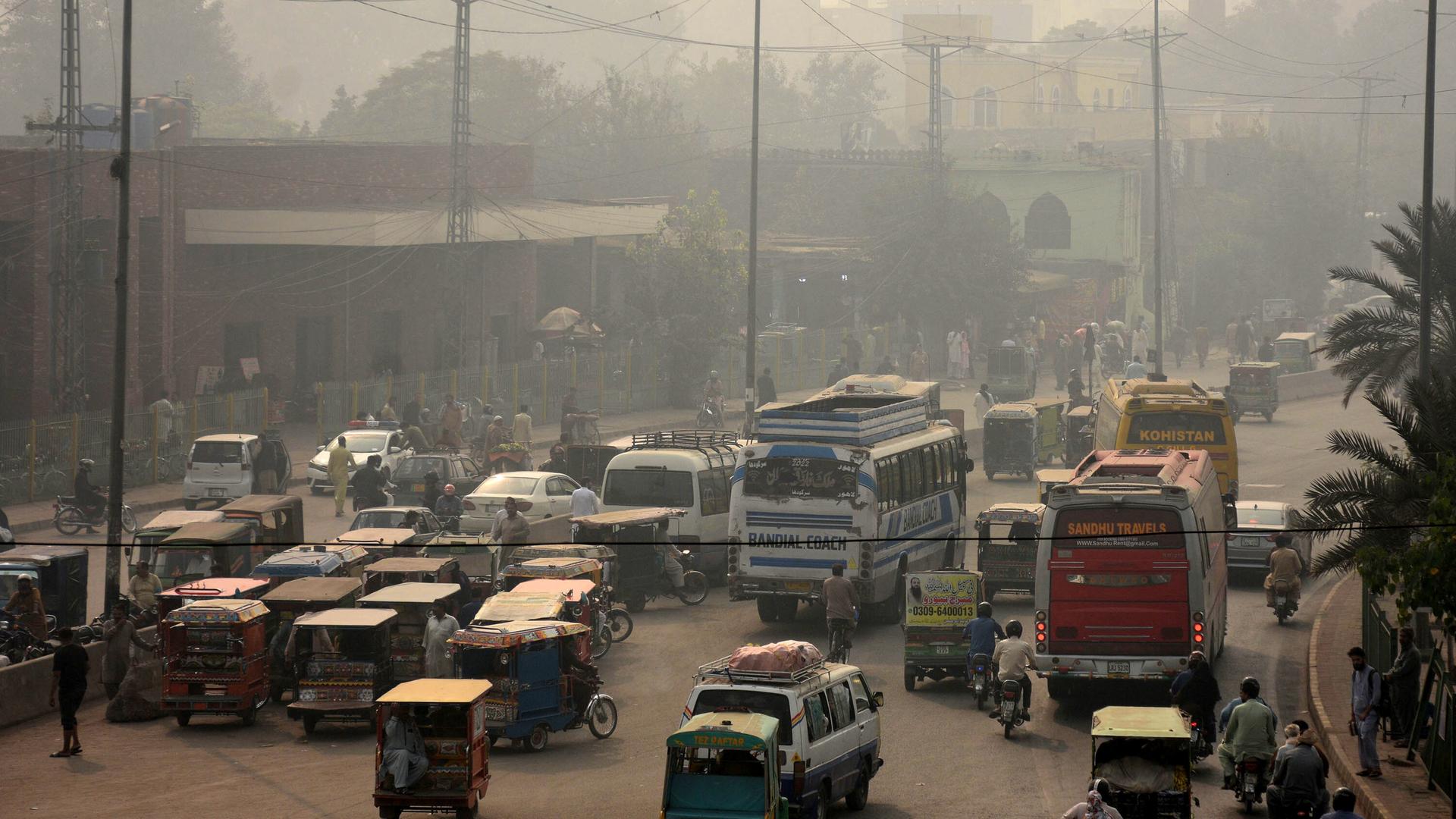 Auf einer von Smog bedeckten Straße in Lahore, Pakistan, fahren viele Fahrzeuge.