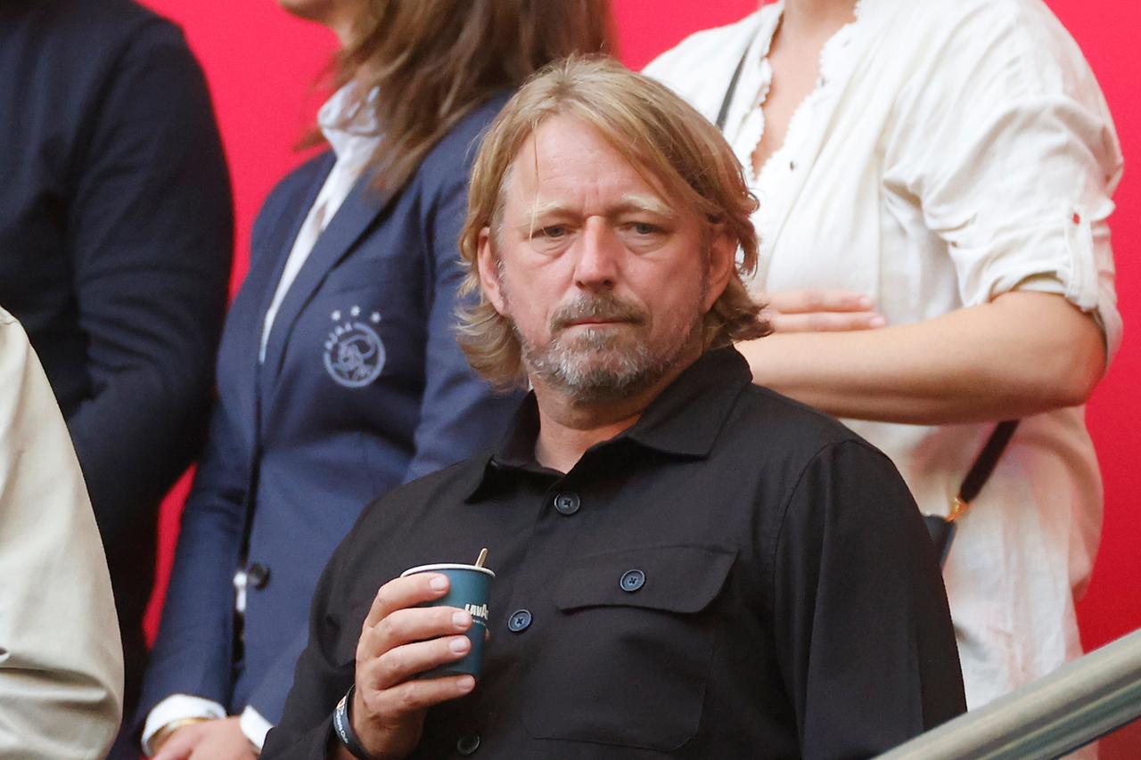 Der Ex-Fußballdirektor von Ajax Amsterdam, Sven Mislintat, auf der Tribüne während eines Spiels von Ajax Amsterdam. Er hält einen Pappbecher mit Kaffee in der Hand. 