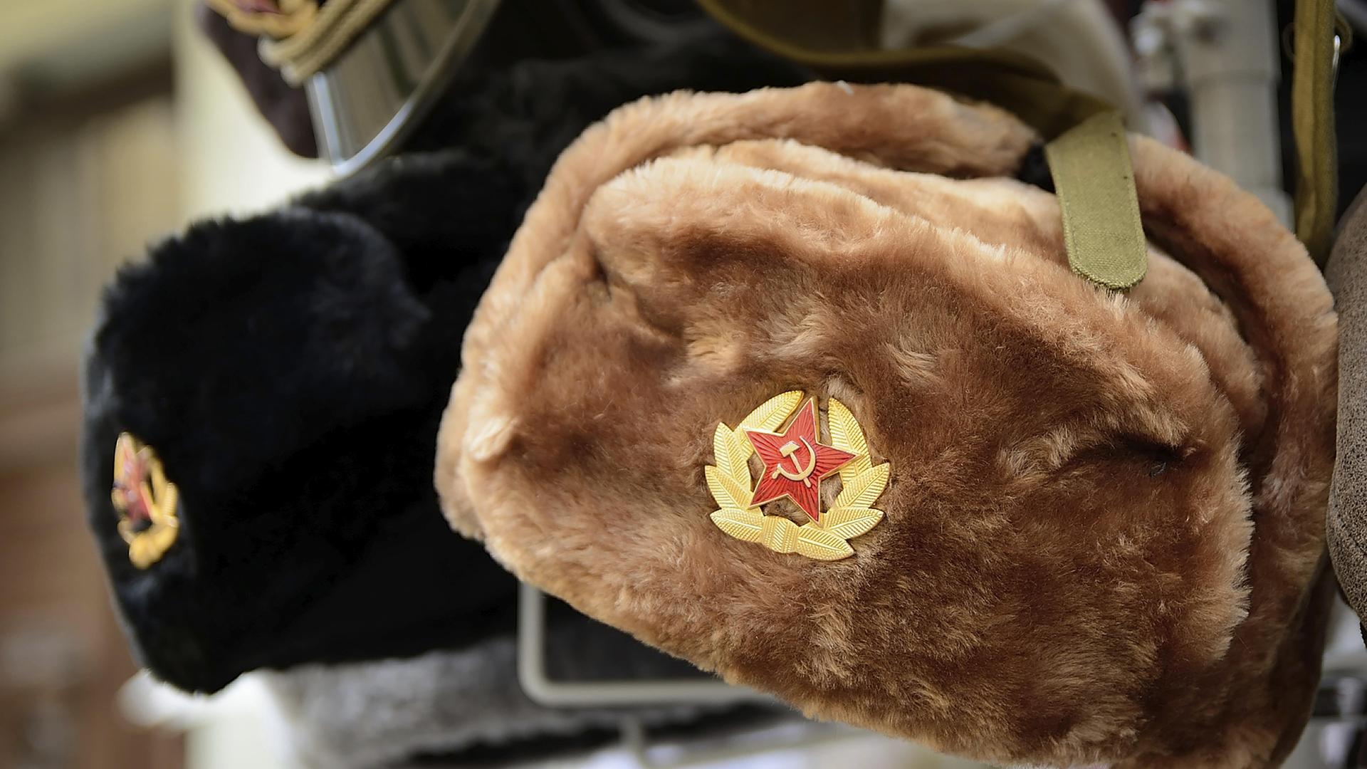 Traditionelle russische Wintermützen, die mit sowjetischen Abzeichen verziert sind, werden in einem Souvenirladen zum Verkauf angeboten.