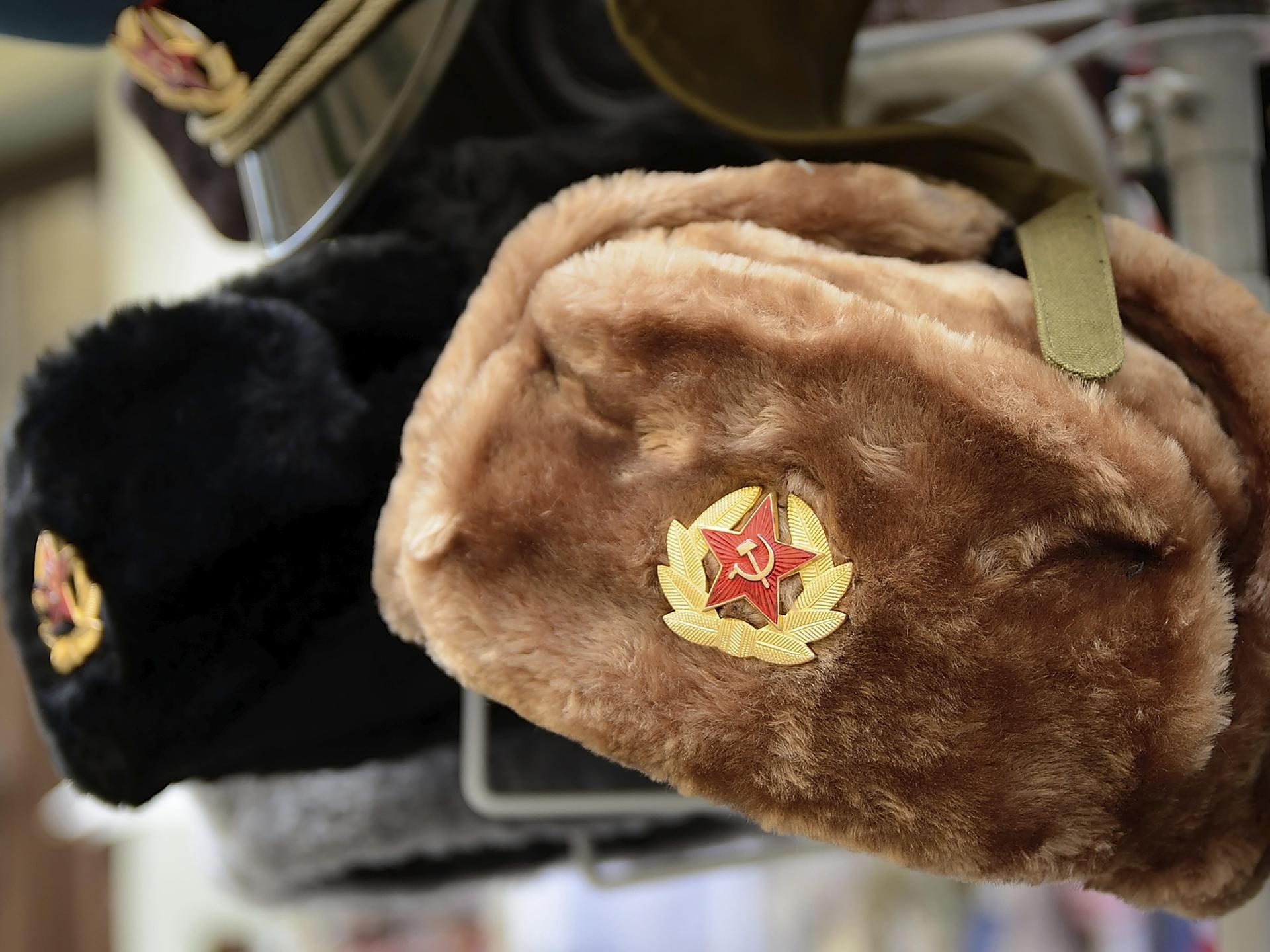 Traditionelle russische Wintermützen, die mit sowjetischen Abzeichen verziert sind, werden in einem Souvenirladen zum Verkauf angeboten.