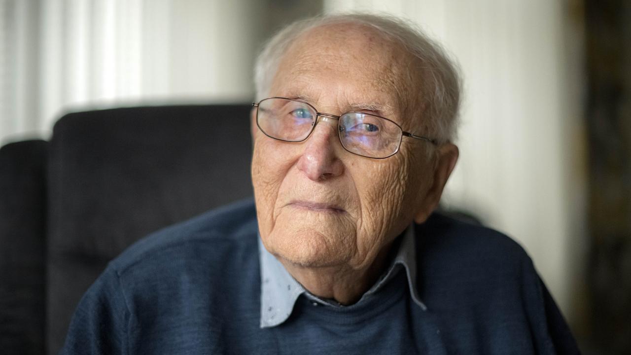 Der Holocaust-Überlebende Albrecht Weinberg trägt Brille und einen blauen Pullover und blickt mit ruhigem, ernsten Blick in die Kamera. 