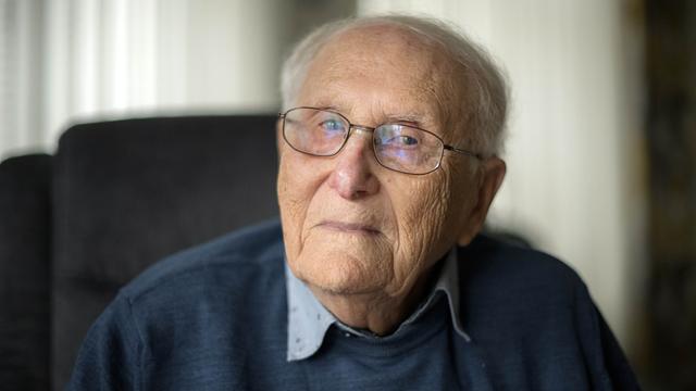 Das Foto zeigt Albrecht Weinberg. Er trägt eine Brille und einen blauen Pullover und guckt direkt in die Kamera. 