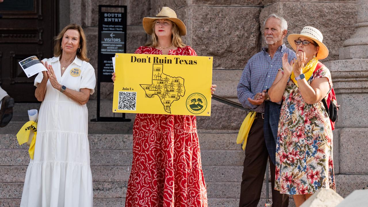 Vier Personen stehen bei einer Demonstration auf einer Straße. Eine Frau in rotem Kleid hält ein gelbes Schild in die Luft, auf dem "Don't ruin Texas" steht.
