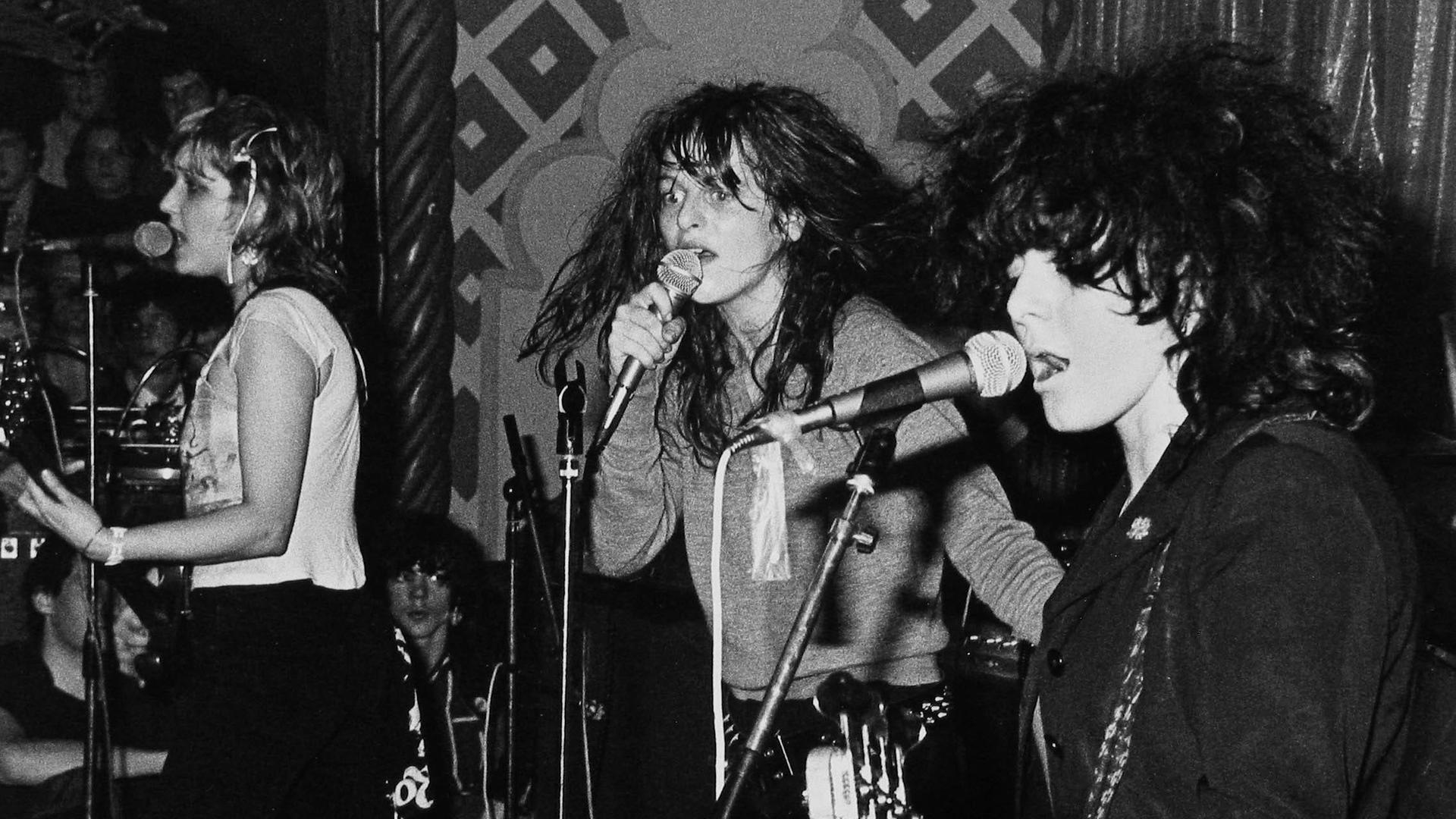 Ein Schwarz-Weiß-Foto zeigt Viv Albertine, Ariane Foster und Tessa Pollitt von der Band The Slits bei einem Auftritt im Mai 1979

