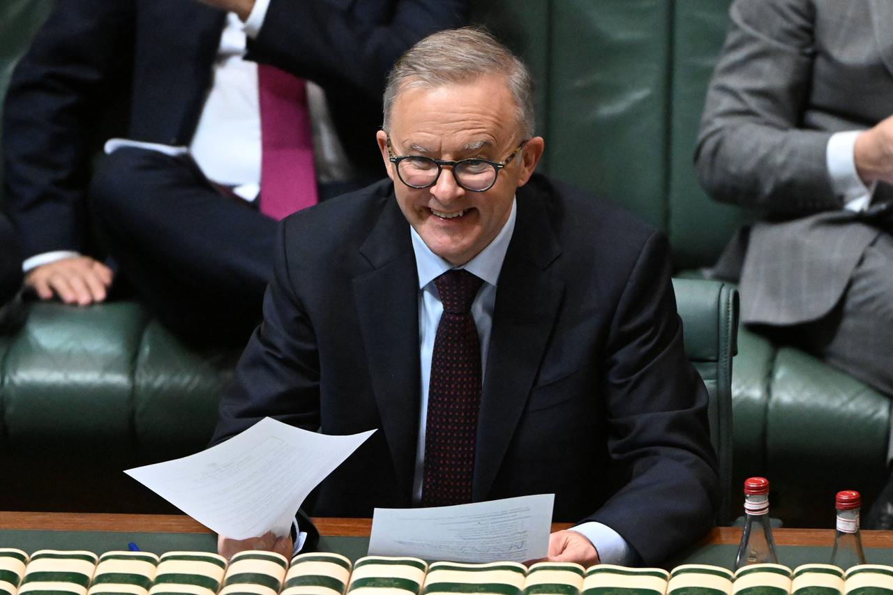 Der australische Premierminister Albanese sitzt an einem Tisch, hat zwei Blätter in der Hand und lächelt. Der australische Premierminister Albanese sitzt an einem Tisch, hat zwei Blätter in der Hand und lächelt.