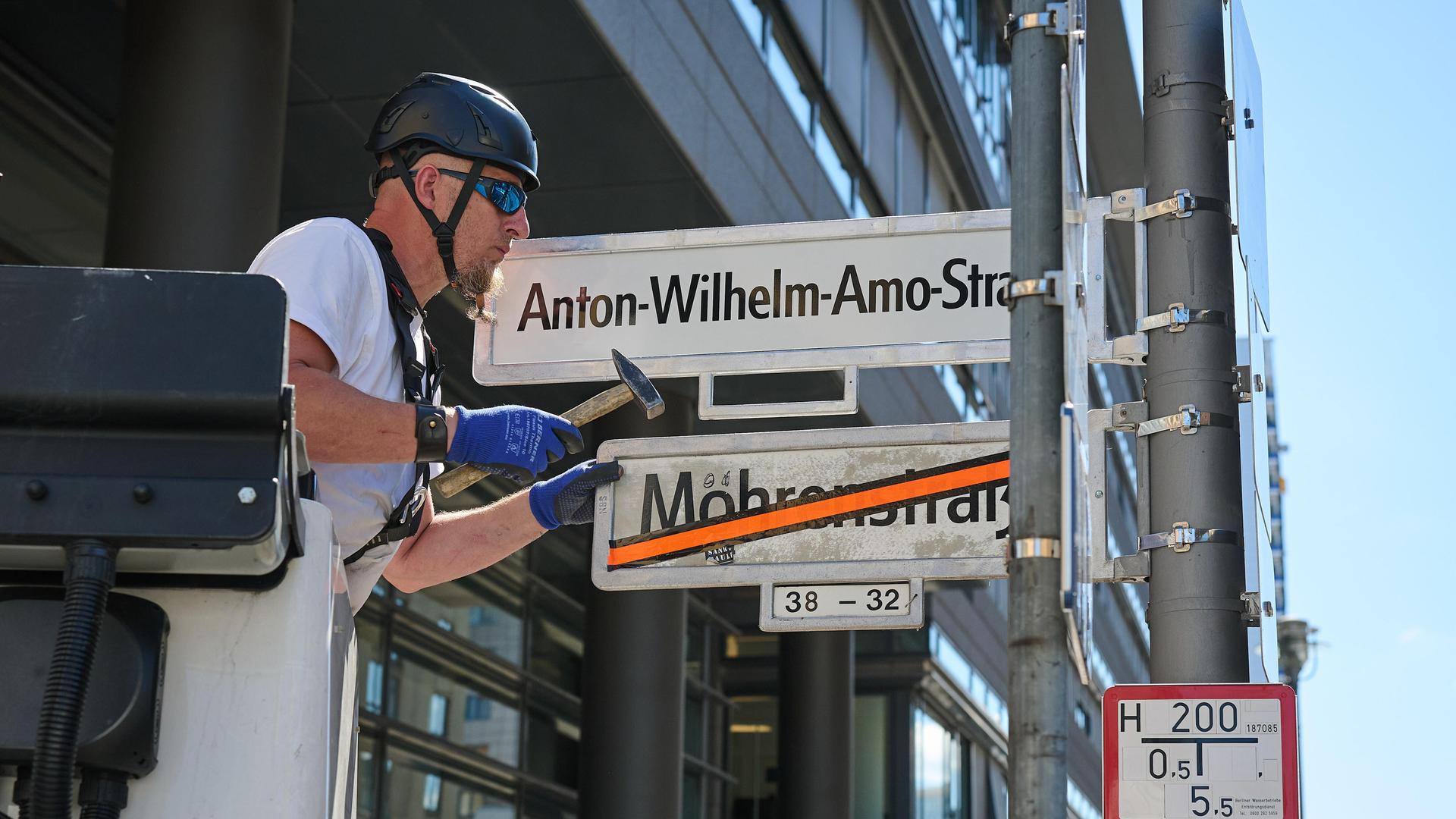Ein Mann tauscht Straßennamen: Das Schild Mohrenstrasse ist bereits durchgestrichen. Nun wird das Schild mit Anton-Wilhelm-Amo-Straße montiert.