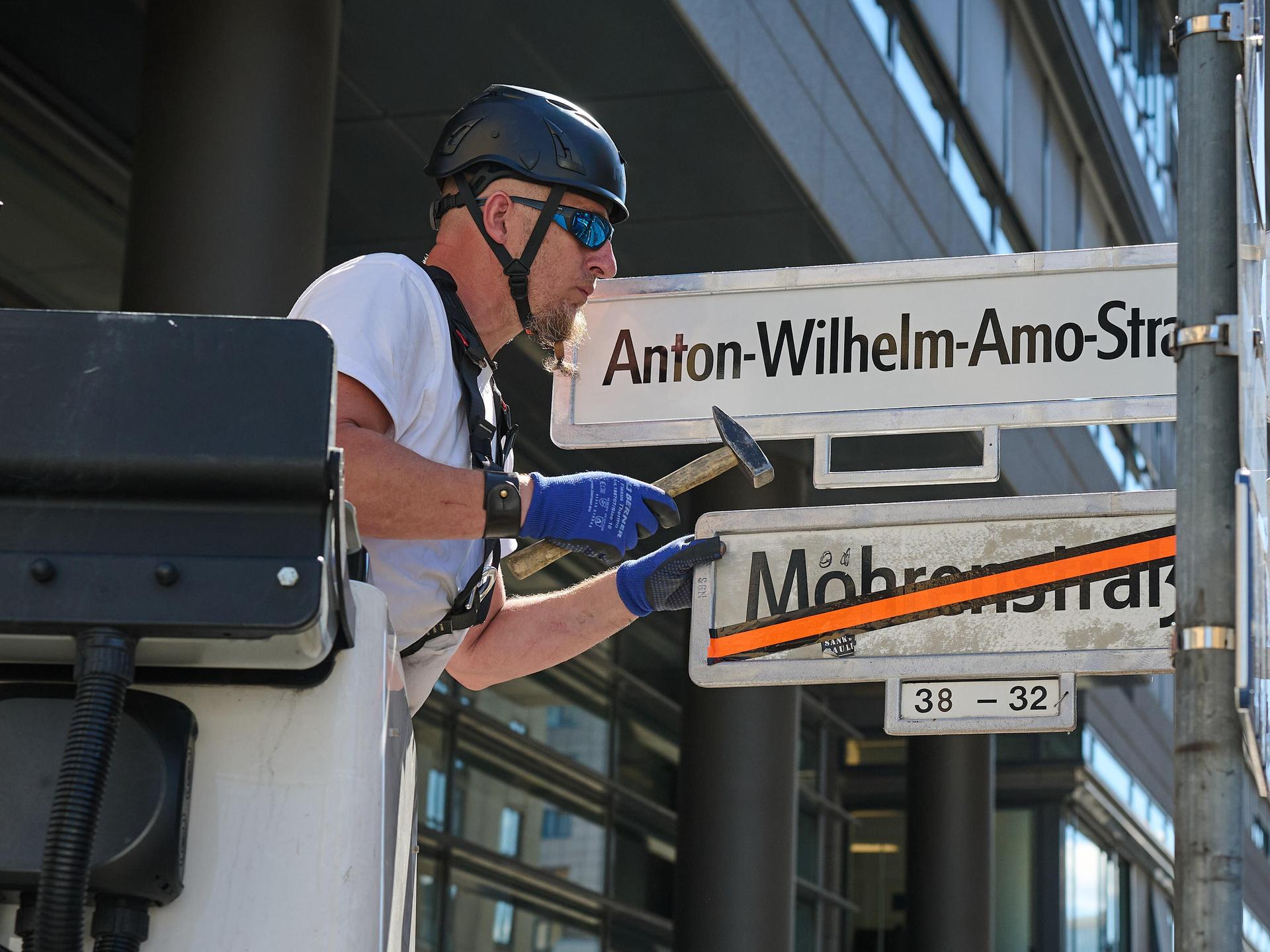 Ein Mann tauscht Straßennamen: Das Schild Mohrenstrasse ist bereits durchgestrichen. Nun wird das Schild mit Anton-Wilhelm-Amo-Straße montiert.