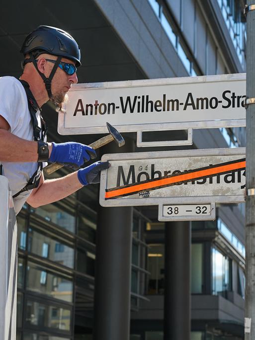 Ein Mann tauscht Straßennamen: Das Schild Mohrenstrasse ist bereits durchgestrichen. Nun wird das Schild mit Anton-Wilhelm-Amo-Straße montiert.