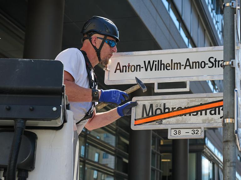 Ein Mann tauscht Straßennamen: Das Schild Mohrenstrasse ist bereits durchgestrichen. Nun wird das Schild mit Anton-Wilhelm-Amo-Straße montiert.