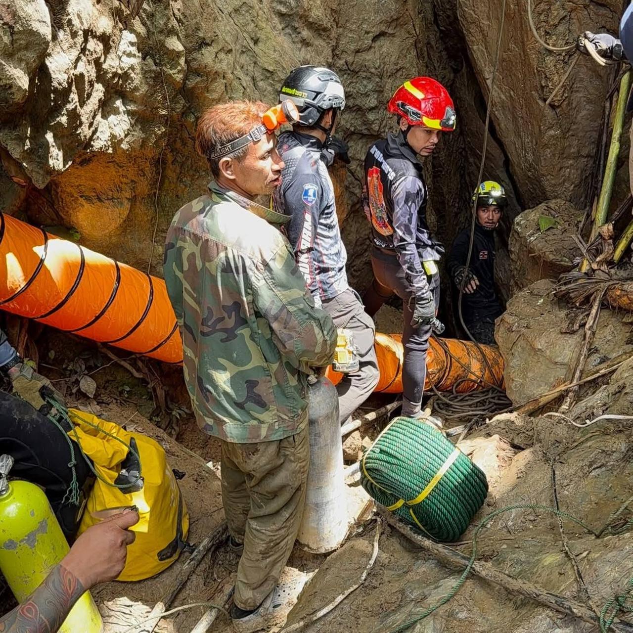 Höhlenretter mit Helmen und Spezialausrüstung am Eingang einer Höhle