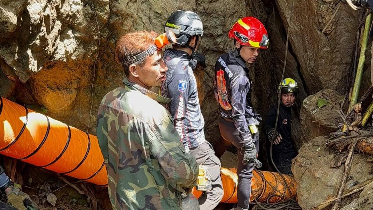 Höhlenretter mit Helmen und Spezialausrüstung am Eingang einer Höhle