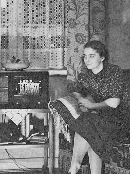 Ein gut bürgerliches Ehepaar sitzt in ihrer Wohnung an einem Volksempfänger.