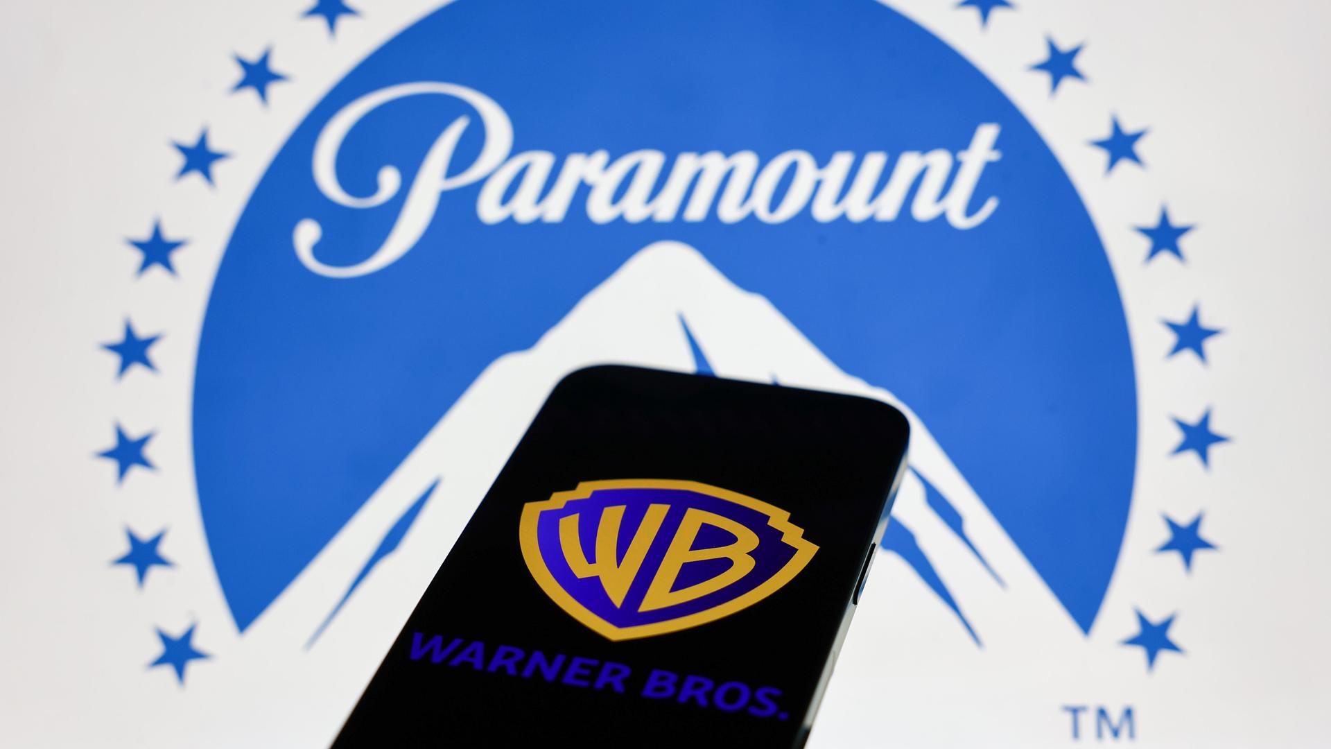 Das Paramount-Logo wird auf einem Laptop-Bildschirm und das Warner Bros.-Logo auf einem Handy-Bildschirm angezeigt.
