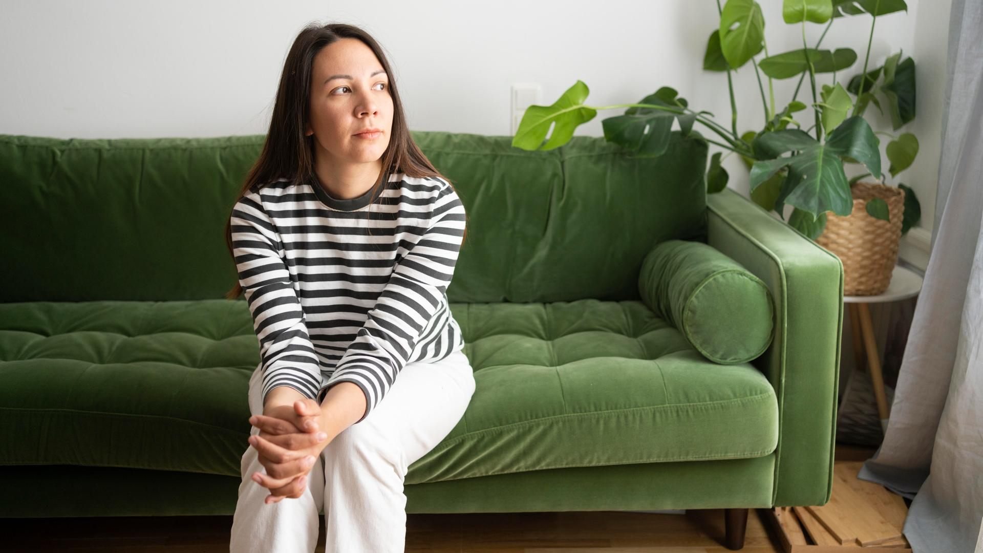 Eine Frau sitzt auf einem grünen Sofa. Eine Frau sitzt auf einem grünen Sofa.