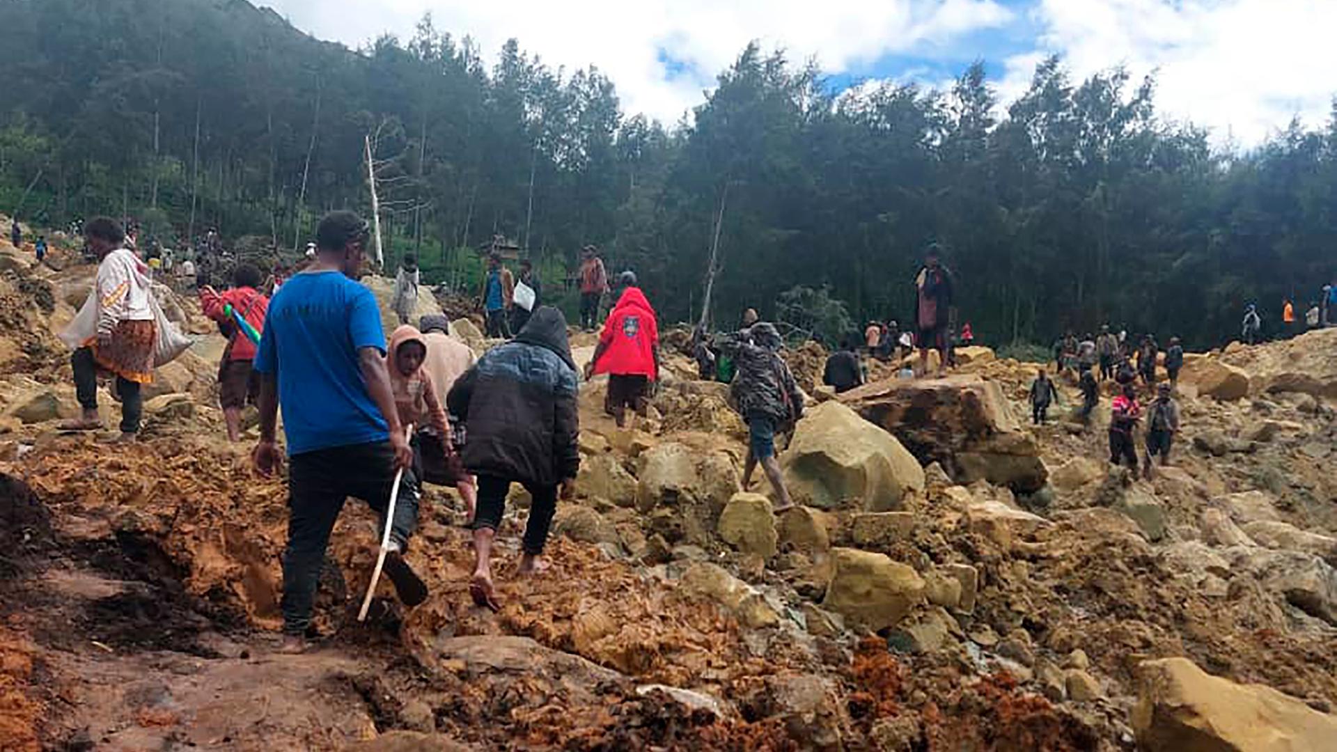 Papua-Neuguinea, Yambali: Auf diesem von der Internationalen Organisation für Migration via AP zur Verfügung gestellten Foto überqueren Menschen den Bereich des Erdrutsches, um auf die andere Seite zu gelangen. Papua-Neuguinea, Yambali: Auf diesem von der Internationalen Organisation für Migration via AP zur Verfügung gestellten Foto überqueren Menschen den Bereich des Erdrutsches, um auf die andere Seite zu gelangen.