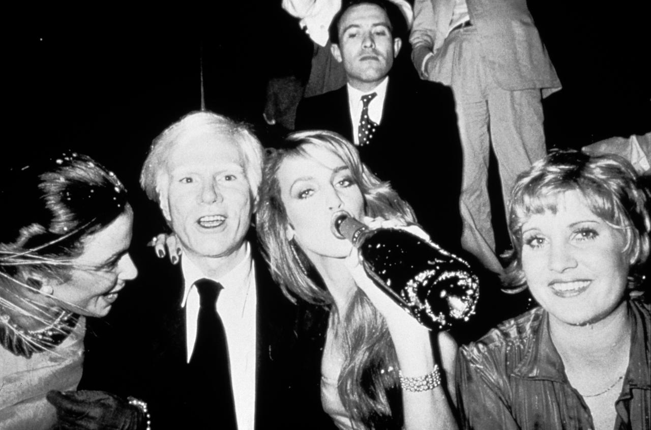 Lächelnde Menschen in Partystimmung, eine Frau trinkt Champagner aus der Flasche.