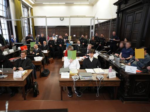 Die Angeklagten des Prozesses gegen die rechtsextreme Terrorgruppe "Letzte Verteidigungswelle" verdecken ihre Gesichter mit roten, grünen und gelben Papierordnern im Hamburger Oberlandesgericht.