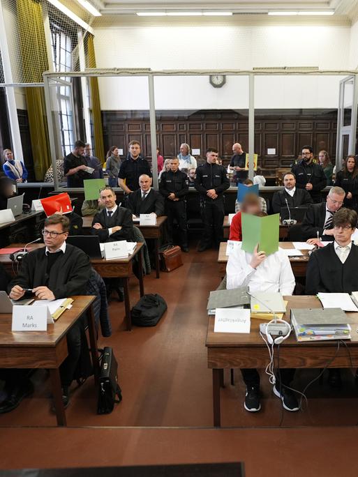 Die Angeklagten des Prozesses gegen die rechtsextreme Terrorgruppe "Letzte Verteidigungswelle" verdecken ihre Gesichter mit roten, grünen und gelben Papierordnern im Hamburger Oberlandesgericht.