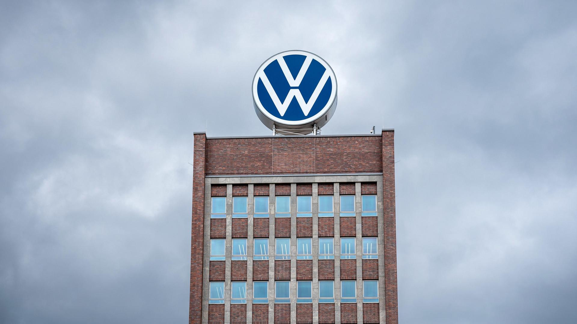 Markenhochhaus des Volkswagenwerks Wolfsburg vor dunklen Wolken.