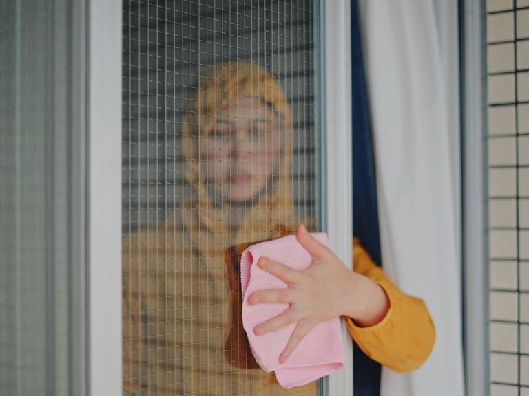 Portrait einer Fenster putzenden Frau.