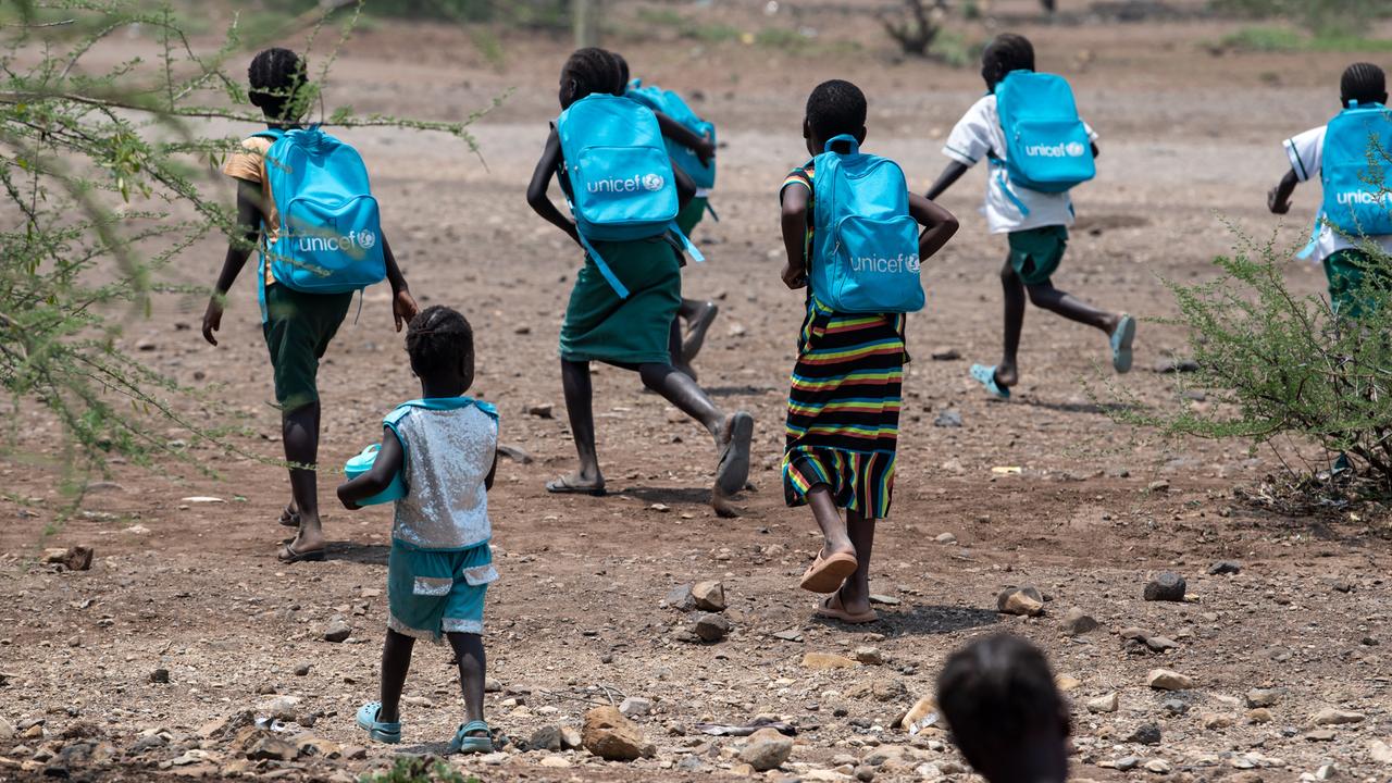Das Foto zeigt Kinder in Kenia. Sie tragen blaue Schulrucksäcke von Unicef. 