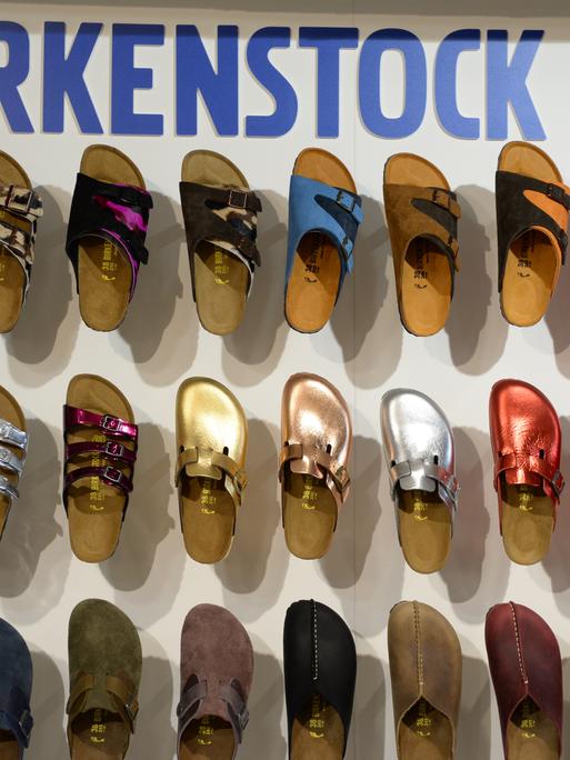 Schuhe von Birkenstock hängen an einer Wand zur Präsentation