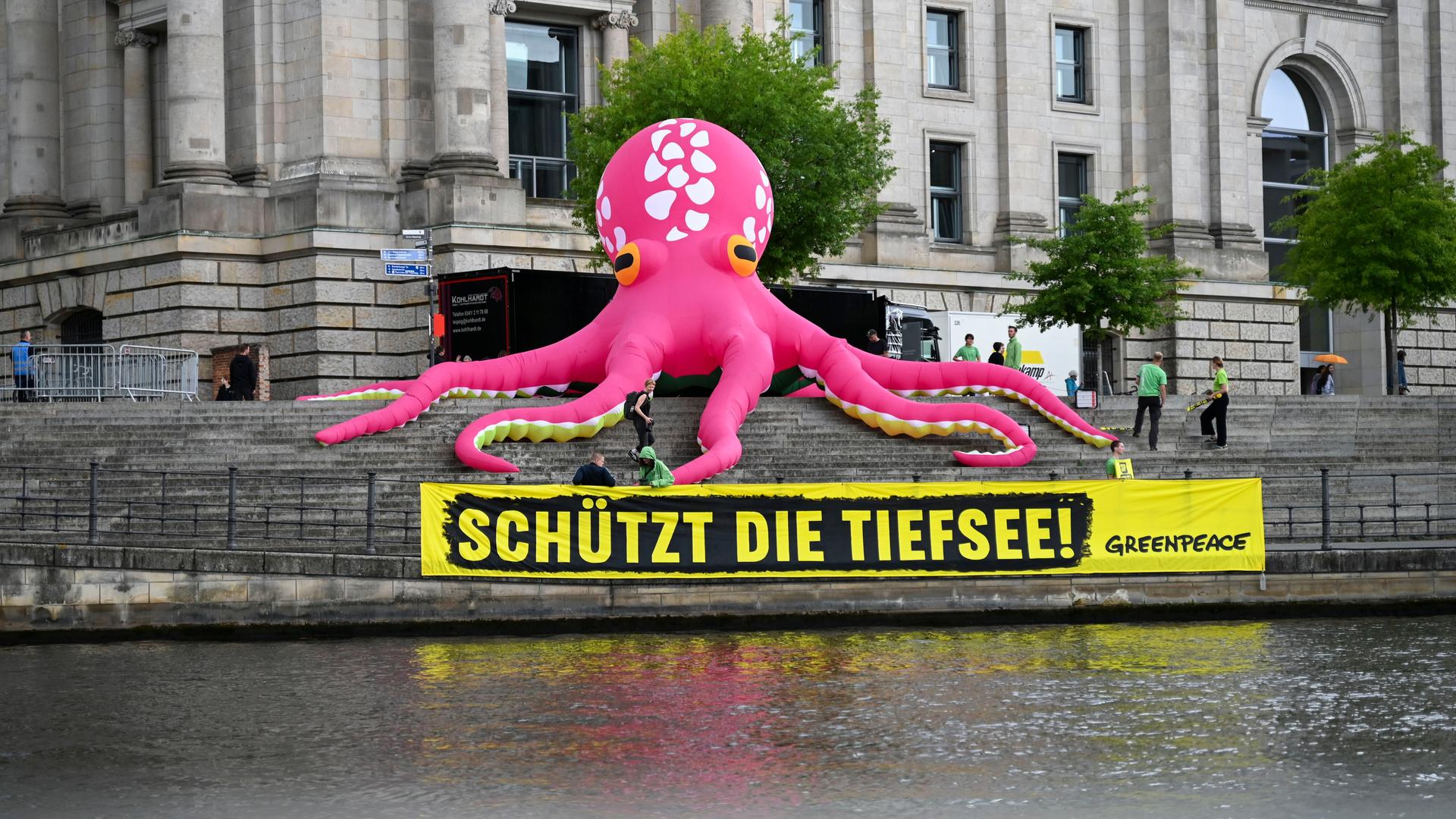 Ein aufblasbarer pinkfarbener Oktopus steht auf den Treppen am Reichstagsufer in Berlin.