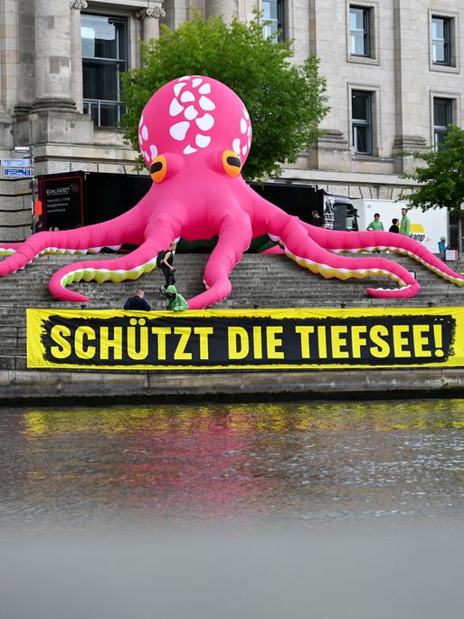 Ein aufblasbarer pinkfarbener Oktopus steht auf den Treppen am Reichstagsufer in Berlin.