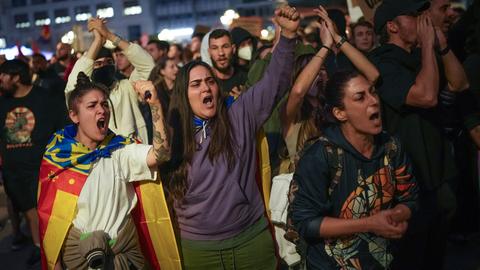 Zu sehen sind wütende Menschen auf einer abendlichen Demonstration in Valencia, Spanien. Sie fordern den Rücktritt des dortigen Regionalpräsidenten. 