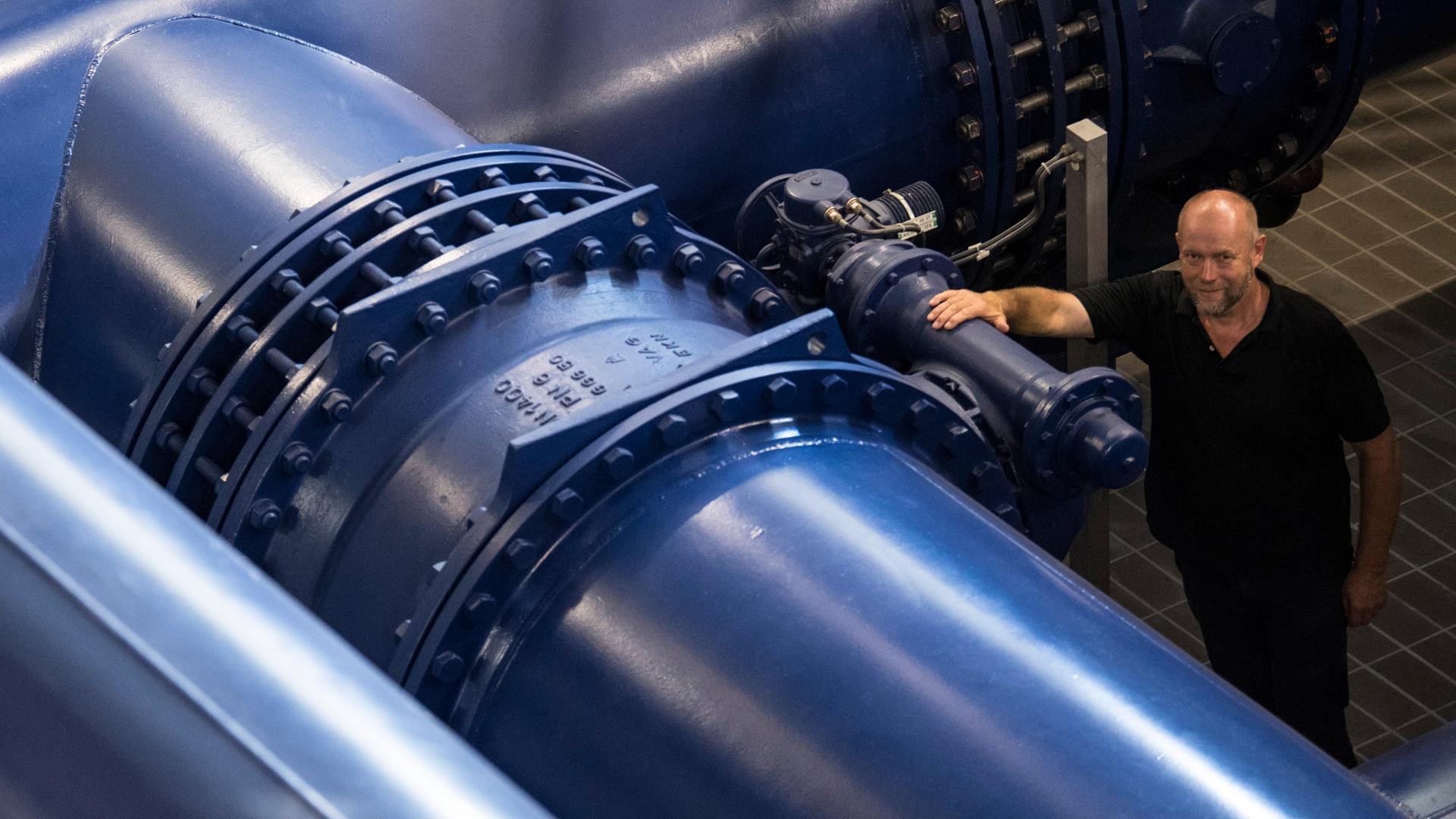 Walter Klupp, ein Hessenwasser-Mitarbeiter, steht auf dem Foto von 2018 zwischen riesigen, blauen Wasserrohren in der Rheinwasseraufbereitungsanlage. Walter Klupp, ein Hessenwasser-Mitarbeiter, steht auf dem Foto von 2018 zwischen riesigen, blauen Wasserrohren in der Rheinwasseraufbereitungsanlage.