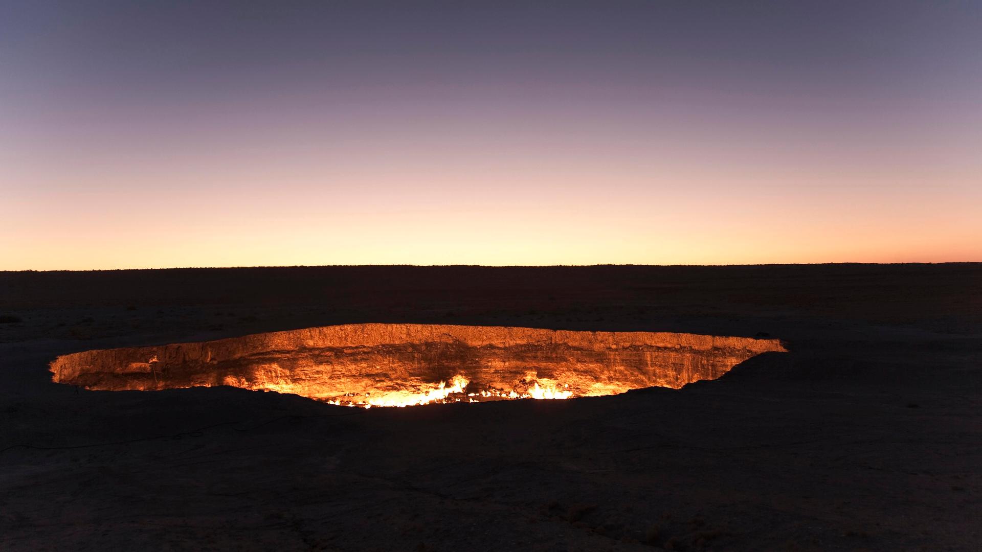 Ein Feuerkrater inmitten einer nächhtlich-dunklen Landschaft.