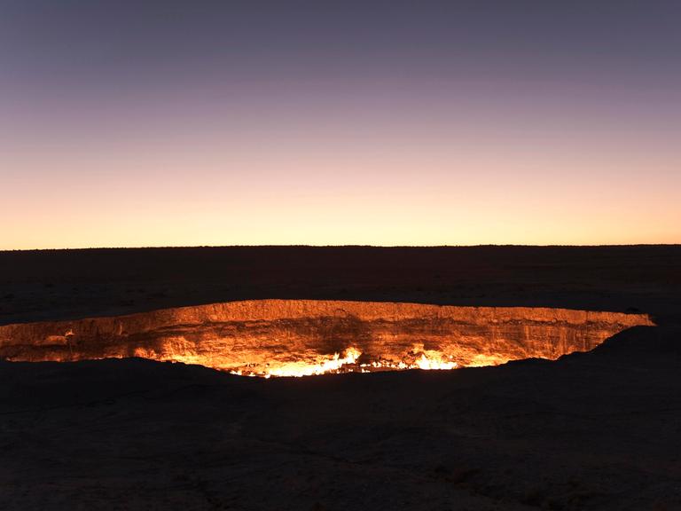 Ein Feuerkrater inmitten einer nächhtlich-dunklen Landschaft.