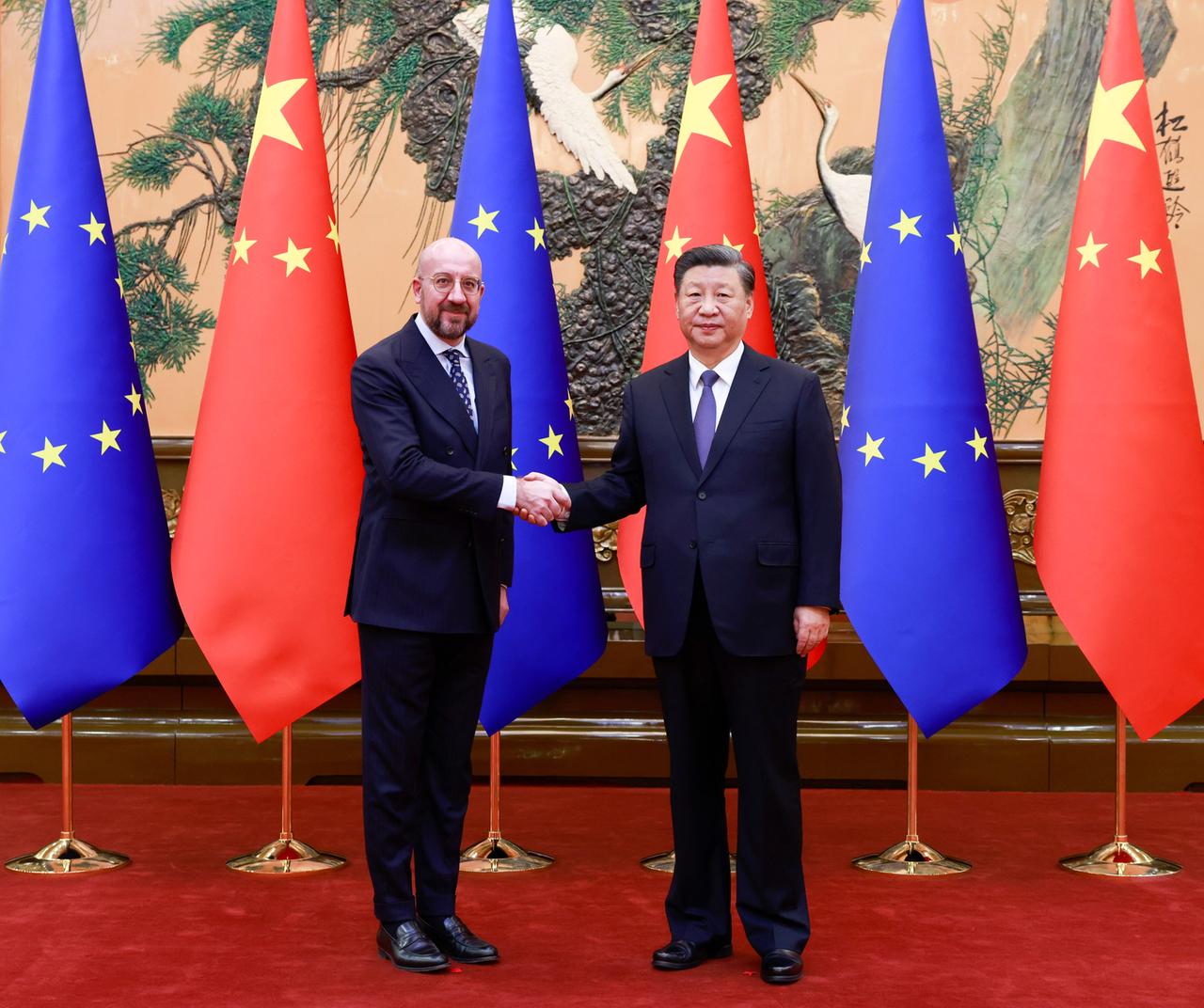 Der Präsident des Europäischen Rates, Michel, und der chinesische Präsident Xi Jinping schütteln sich die Hand. Hinter ihnen jeweils drei EU- und chinesische Flaggen.
