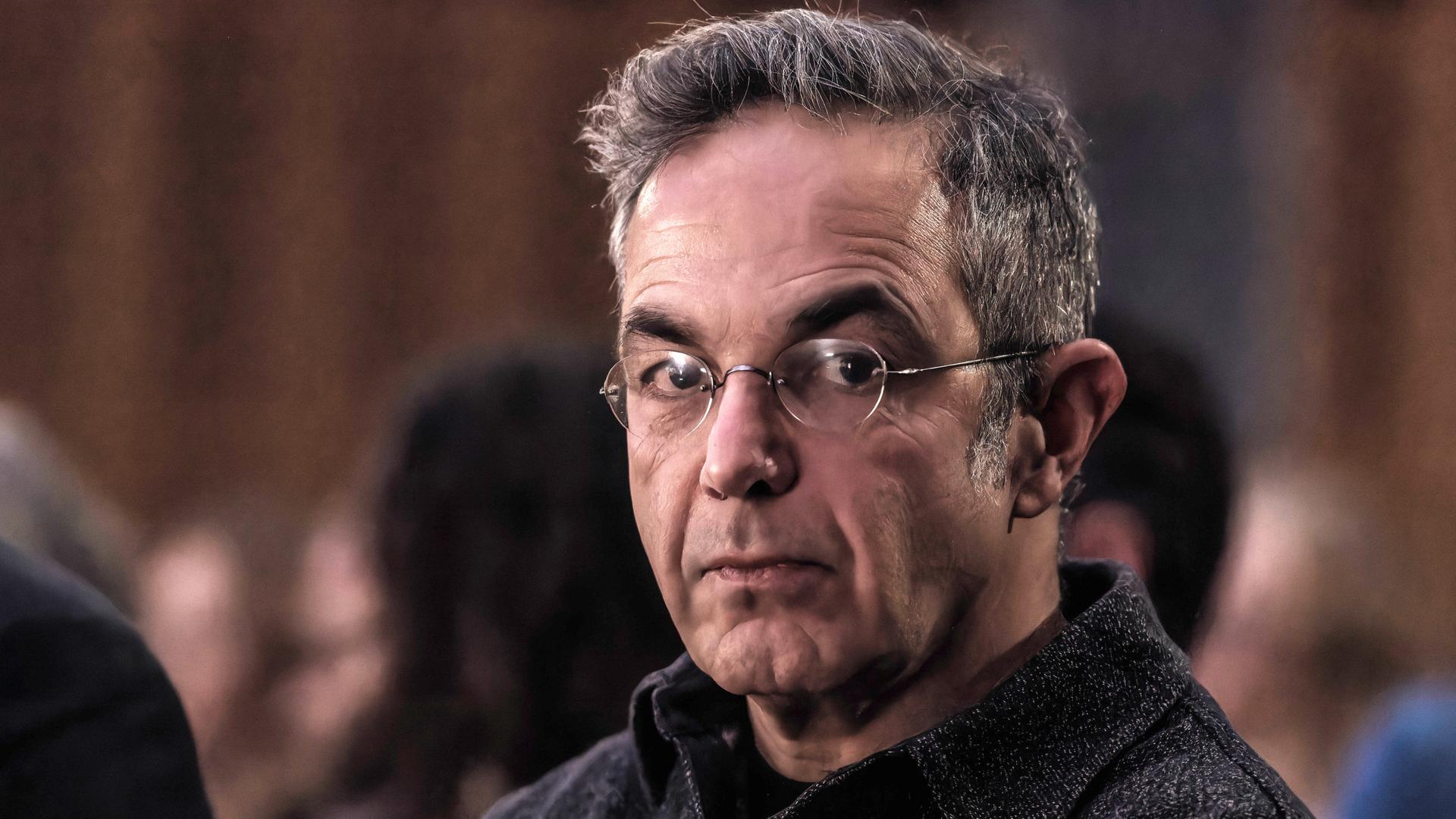Navid Kermani, mit Brille, in einem dunklen Hemd, blickt ernst in die Kamera.