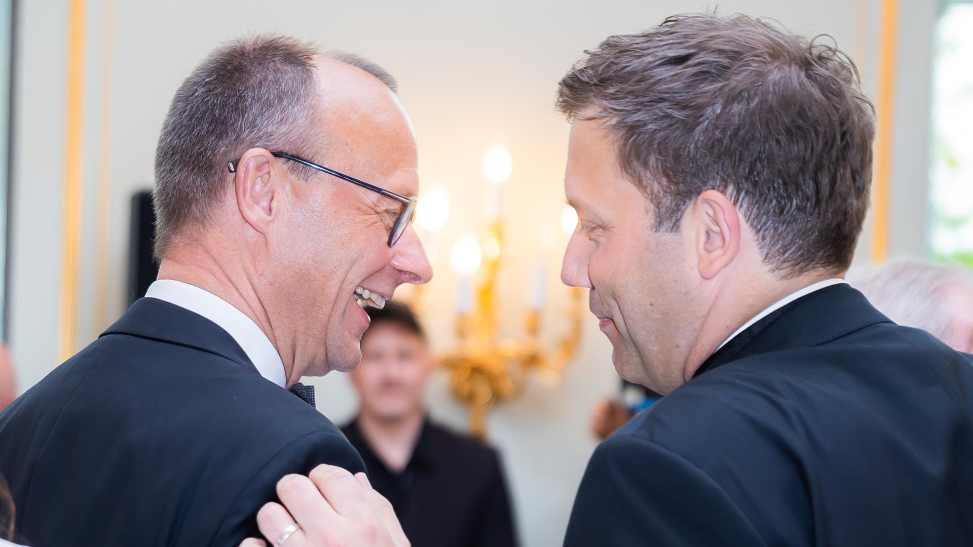 Friedrich Merz und Lars Klingbeil lachen zusammen und klopfen sich auf die Schulter.