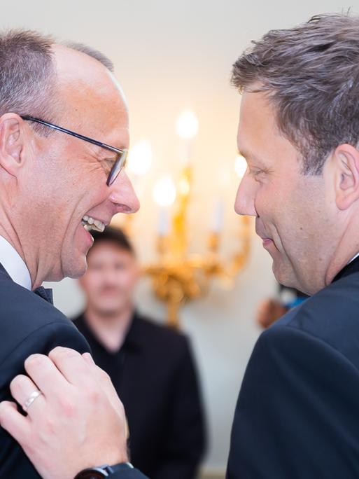 Friedrich Merz und Lars Klingbeil lachen zusammen und klopfen sich auf die Schulter.