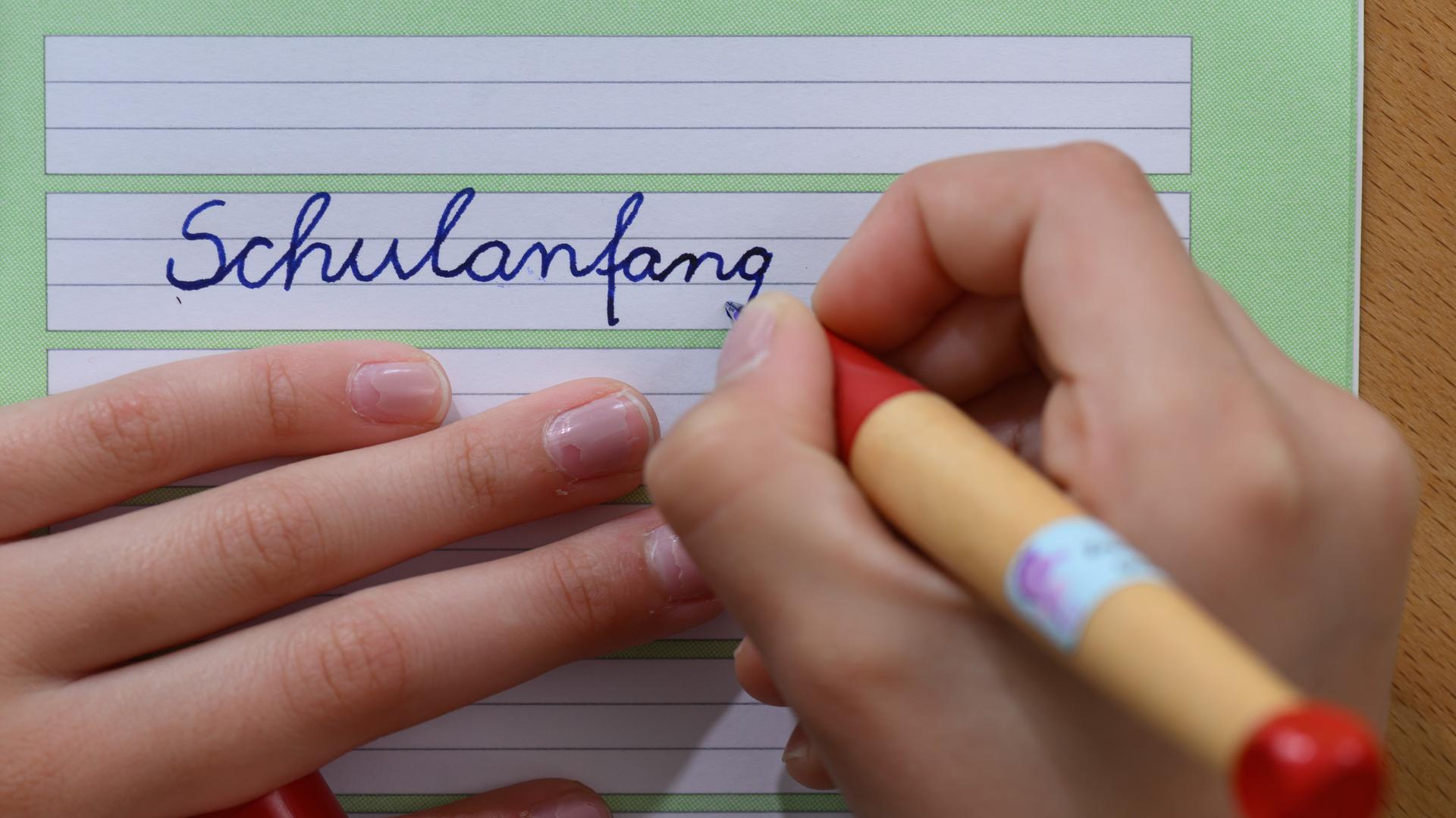 Ein Mädchen schreibt das Wort "Schulanfang" in ein Schreibheft. Ein Mädchen schreibt das Wort "Schulanfang" in ein Schreibheft.